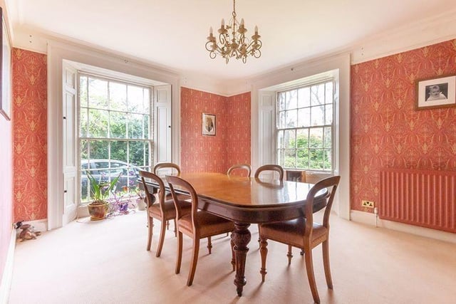The dining  room, which has sash windows to two elevations with shutters and a traditional fireplace with open grate.