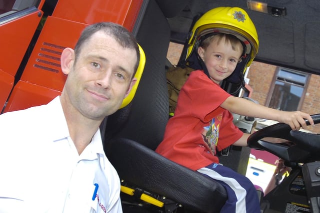 A young boy sits in a fire engine.