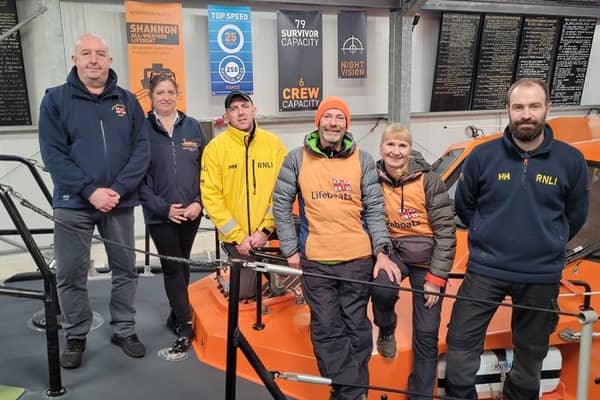 Antony and Sally (orange Hi-Vis vests) with members of Seahouses Lifeboat Crew. L to R Crew Members John Parkin, Lynsey Carr, Iain Saunders, walkers Antony and Sally, and Station Mechanic Graeme Trotter.