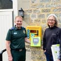 Paul Brolly and Beck Orton with the new defibrillator at Cambo Village Hall.