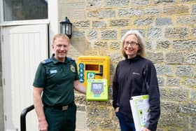 Paul Brolly and Beck Orton with the new defibrillator at Cambo Village Hall.