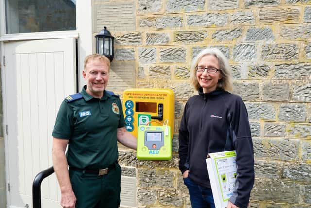 Paul Brolly and Beck Orton with the new defibrillator at Cambo Village Hall.