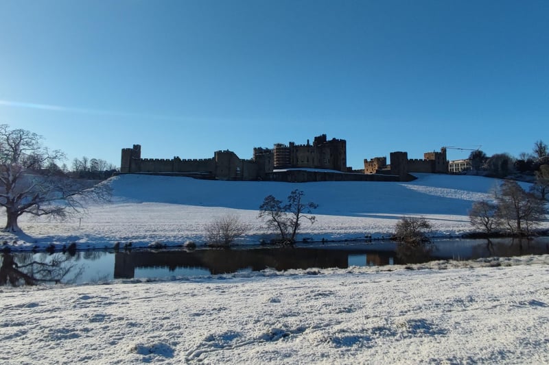 The snow-covered Pastures and Alnwick Castle with the River Aln.