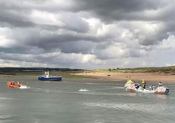 The Amble RNLI inshore lifeboat tows the rowing boat towards Amble harbour.