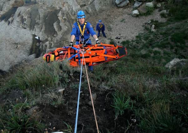 A Coastgaurd rope rescue technician brings a casualty up a cliff in a stretcher in a simulated rescue.