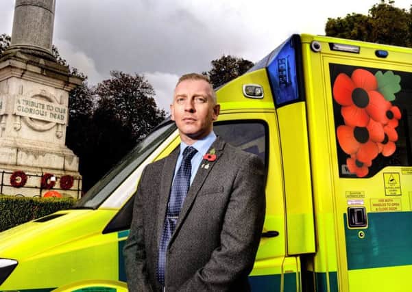 David Parkin with one of the poppy ambulances. Picture by Doug Pittman