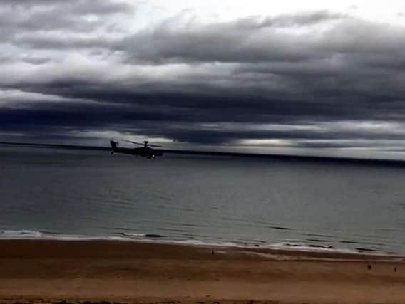 The Apache helicopter flies low past Bamburgh Castle.