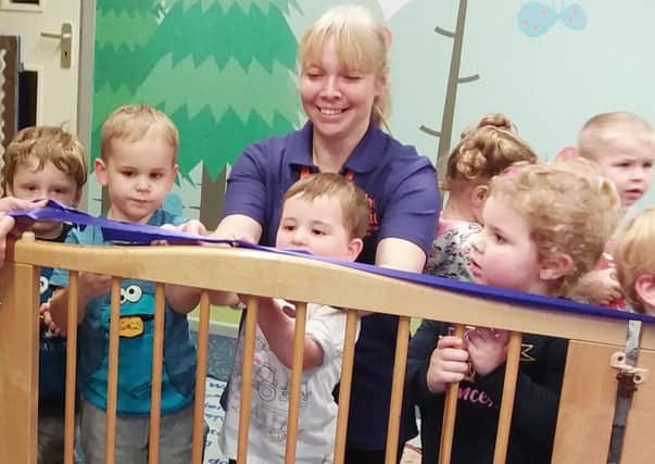 Nursery officer Wendy Robinson cuts the ribbon, with some of the children who attend Cubs & Kits Preschool Alnwick.