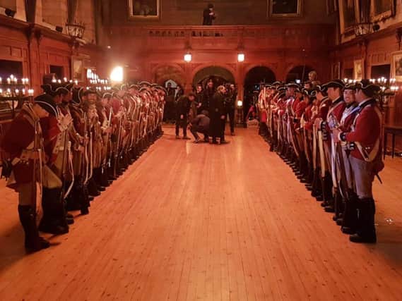 Supporting artists (extras) lined up in the King's Hall at Bamburgh Castle during filming for Frontier.