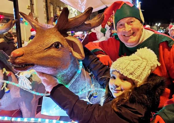 Alnwick Lions sleigh was pulled by two new reindeer and Grace McEwan, pictured here with one of Santa's helpers, named them Snowflake and Frosty. Picture by Jane Coltman