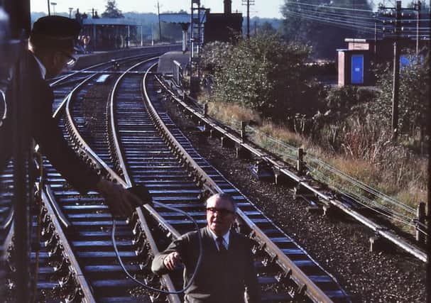 A train in Norfolk in 1981. The driver gives the staff to the signalman.
