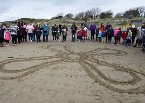 Lowick and Holy Island schoolchildren and villagers with the St Cuthbert's cross drawn in the sand. Picture by Jane Coltman