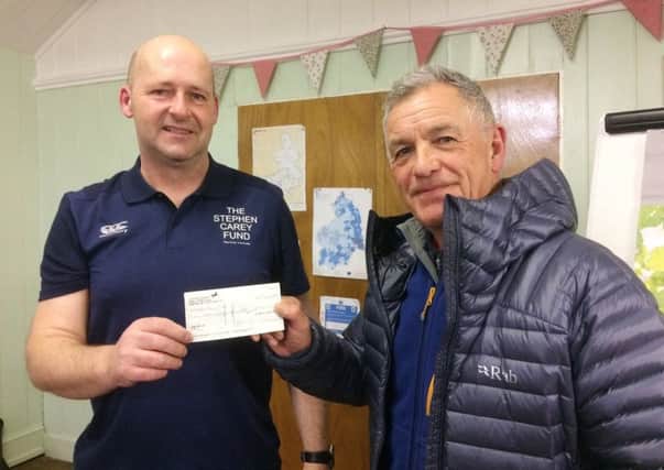 Gustave MacLeod, chairman of Ellingham Village Hall committee, presents a cheque for £160, raised at a coffee morning, to Dougie McEwan, from The Stephen Carey Fund.