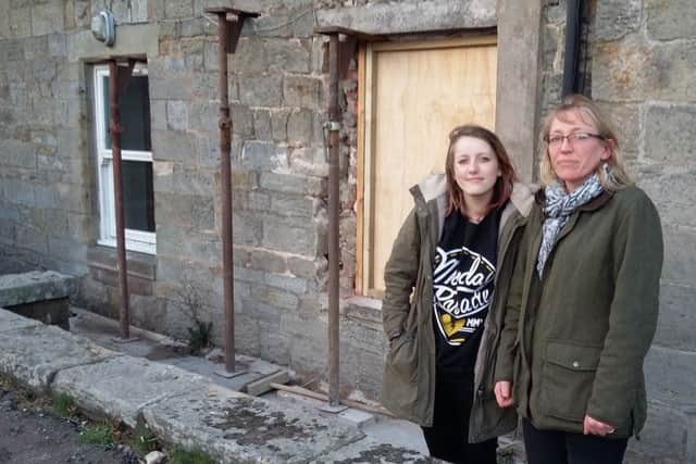 Charlotte and Helen Wyld outside their house, with the boarded-up window beside them.