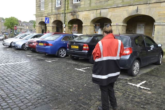 A civil enforcement officer checks the cars parked in Alnwick Market Place. 
Picture by Jane Coltman