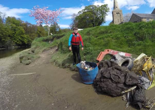 Archie McNaughton on the banks of the River Coquet with the rubbish he and his dad collected.