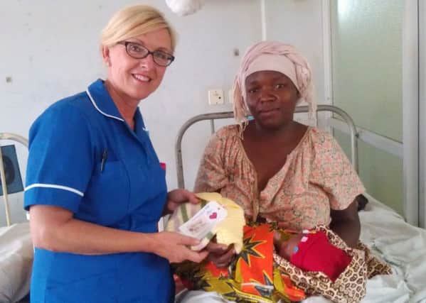 Northumbria midwife Julie Howe gives one of the Knitted with Love garments to a mum and baby at Kilimanjaro Christian Medical Centre in Tanzania.