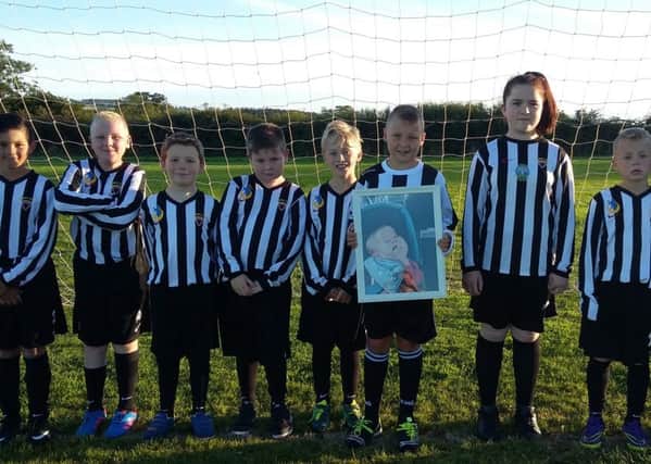 Alnwick Town U10s are running the Junior Great North Run in memory of Aidan Jackowiak Smith. His cousin, Jack Milligan, holds a picture of Aidan.