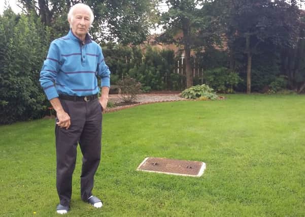 Jim Henderson in his back garden, beside the manhole cover. The sewage flooded the area behind where he is standing.