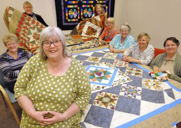 Sue Ross and her quilters with some of their handiwork.