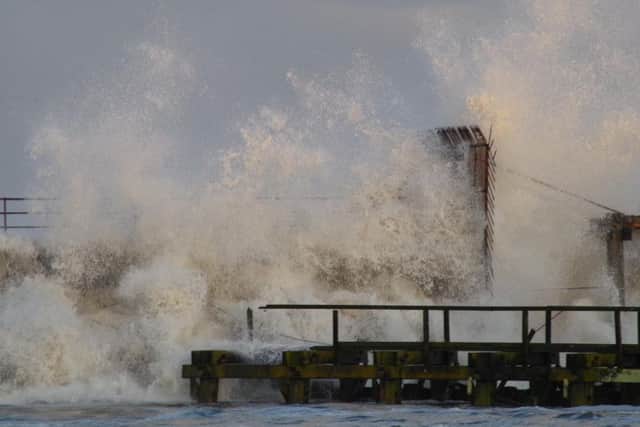 Waves crash over the pier. Picture by John Tuttiett