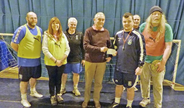 Pictured presenting the cheque to Josh Rutherford, coach of Walking Football scheme, is Rotarian Dave Shoemaker with some of the walking football participants.