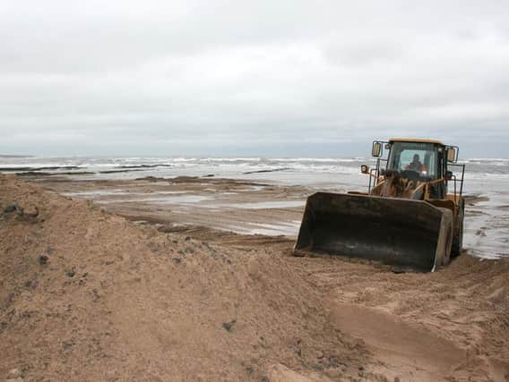A digger moves sand to the foot of the dunes in emergency repair work at Low Hauxley. Picture by The Ambler