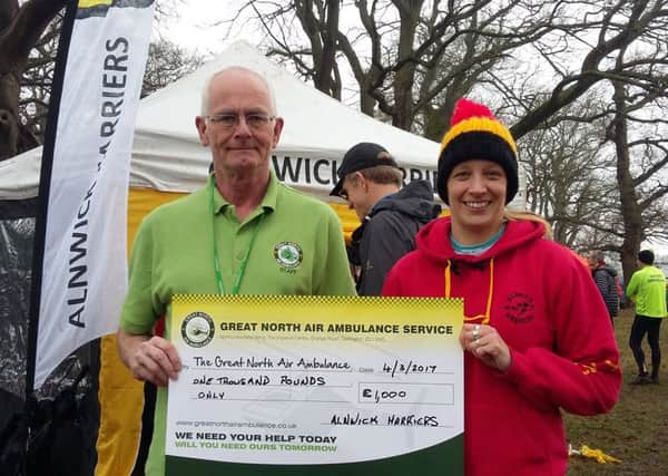 Tracey Sample, chairman of Alnwick Harriers, presents the cheque of Â£1,000 to David Gibson, from the Great North Air Ambulance Service.