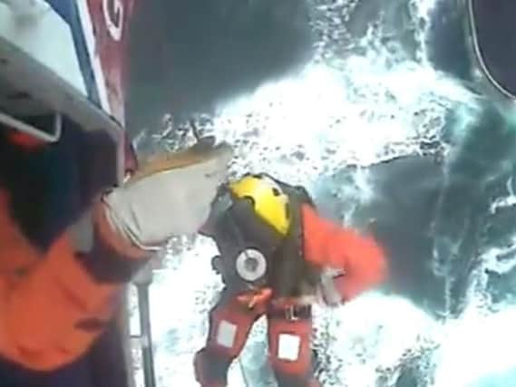 The winchman is lowered from the helicopter in this picture taken from the HM Coastguard video of the rescue.