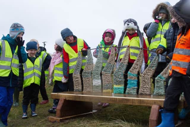 Pupils from Lowick and Holy Island schools admire the new seat that
was made using designs that they had created.