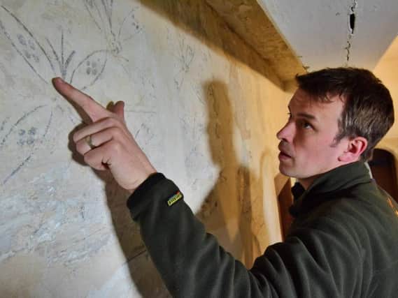Nick Lewis inspects the wall paintings.