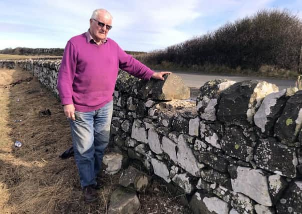 Farmer Billy Curry at the vandalised wall and litter-strewn field near the coastal path near Howick.