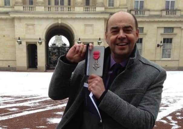 Michael Burgess, who has been manager of the Phoenix Detached Youth Project since he helped to create it in 2004, with his MBE award outside Buckingham Palace.