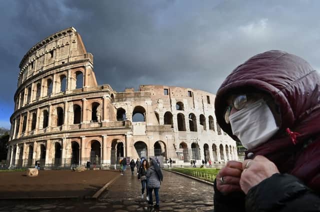 A man wearing a protective mask passes by the Coliseum in Rome (Photo: ALBERTO PIZZOLI/AFP via Getty Images)